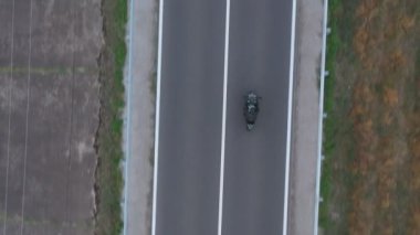 Motosikletli birinin kır yolunda motosikletiyle yarışması. Yolculuk sırasında bisiklet süren bir adam. Havadan bakıldığında, kırsal kesimde motosiklet kullanan bir motosikletli. Özgürlük ve macera kavramı.