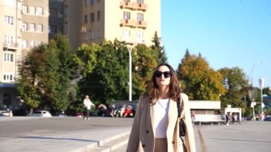 Güzel takım elbiseli genç bayan alışveriş sonrası kaldırımda yürüyen alışveriş çantaları tutuyor. Zarif bir kadın şehir caddesinde kağıt paketler taşıyor. Satış ve indirim kavramı. Yavaş çekim.