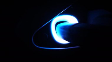 Hand is plugging in power cord to an electric car at night. Man charging electrical auto at evening. Starting the process of refueling battery an EV vehicle. Clean energy filling technology. Close up.