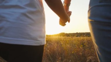 Genç ebeveynler ve çocukları yaz çayırlarında el ele tutuşuyorlar. Anne ve baba gün batımında kızlarıyla çim tarlasında yürüyor. Aile doğada birlikte vakit geçirmekten hoşlanır..