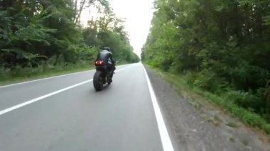 Orman yolunda motosiklet yarışı yapan bir motosikletli. Ormanın yakınındaki kırsal yolda kasklı bir adam spor motosikletine biniyor. Yolculuk sırasında bisiklet süren adam. Özgürlük ve macera kavramı. Hava görüntüsü.