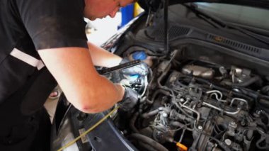 Servis kaputu altında çalışan profesyonel bir tamirci. Genç oto tamircisi atölyedeki arabanın motorunu tamir ediyor. Erkek tamirci garajdaki otomobil motorunu kontrol ediyor. Taşıma tanısı konsepti.