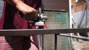 Profesyonel tamircinin erkek elleri özel bir enstrüman tutuyor ve paslı havadan metal yapısını temizliyor. Genç işçilerin kolları demir parçalarını elektrikli testere ile öğütüyor. Kapat..