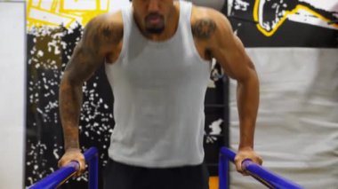Spor kulübünde paralel barlarda şınav çeken güçlü bir Afrikalı atlet. Dövmeli kaslı Afro-Amerikan sporcu modern spor salonunda sıkı egzersizler yapıyor. Sağlıklı ve aktif yaşam tarzı kavramı. Yavaş çekim.