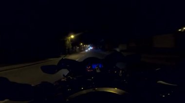 Akşamları yüksek hızda motosiklet kullanan motosiklet sürücüsünün bakış açısı. Aydınlanmış şehir sokaklarında modern spor bisikleti süren erkek motosikletçi. Özgürlük kavramı. POV