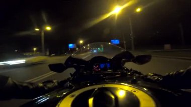 Akşamları yüksek hızda motosiklet kullanan motosiklet sürücüsünün bakış açısı. Aydınlanmış şehir sokaklarında modern spor bisikleti süren erkek motosikletçi. Özgürlük kavramı. POV