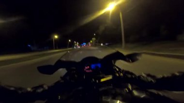 Akşamları yüksek hızda motosiklet kullanan motosiklet sürücüsünün bakış açısı. Aydınlanmış şehir sokaklarında modern spor bisikleti süren erkek motosikletçi. Özgürlük kavramı. POV