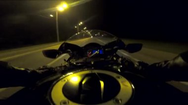 Aydınlanmış şehirde gece vakti bisiklet süren motosikletli bir erkek. Akşamları yüksek hızda motosiklet kullanan motosikletli birinin bakış açısı. Özgürlük kavramı. POV.