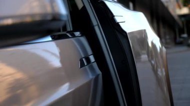 Erkek el elektrikli SUV arabasının arka kapısını açıyor. Elektrikli otomobilin kapısını açmak için düğmeye basan adam. Adam modern otomatiğe oturuyor. Çağdaş teknolojiler kavramı.