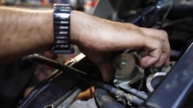 Moto motorunu tamir eden tamircinin erkek elleri. Profesyonel tamirci kolları iş yerinde motosiklet tamirciliği yapıyor. Garajda araba tamir eden yetişkin bir tamirci. Bakım servisi.