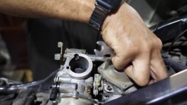 Moto motorunu tamir eden tamircinin erkek elleri. Profesyonel tamirci kolları iş yerinde motosiklet tamirciliği yapıyor. Garajda araba tamir eden yetişkin bir tamirci. Bakım servisi.