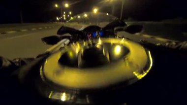 Aydınlanmış şehirde gece vakti bisiklet süren motosikletli bir erkek. Akşamları yüksek hızda motosiklet kullanan motosikletli birinin bakış açısı. Özgürlük kavramı. POV.
