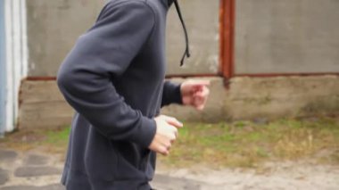 Yağmurlu bir günde kır yolunda koşan atletik bir sporcu. Genç sporcu kırsal alanda koşuyor. Açık havada kardiyo antrenmanı yapan güçlü bir atlet. Sağlıklı aktif yaşam tarzı kavramı. Kapat..