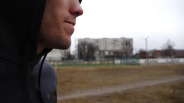 Genç sporcu bulutlu bir günde okul stadyumunda koşuyor. Spor sahasında koşan atletik bir adam. Spor giyim sektöründe güçlü bir adam dışarıda kardiyo eğitimi alıyor. Aktif sağlıklı yaşam tarzı kavramı.