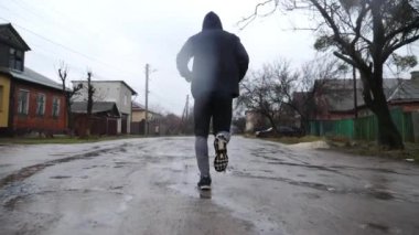 Yağmurda kır yolunda koşan atletik bir sporcu. Genç sporcu bulutlu bir günde kırsal alanda koşuyor. Açık havada spor giyim eğitiminde güçlü bir atlet. Sağlıklı aktif yaşam tarzı kavramı.