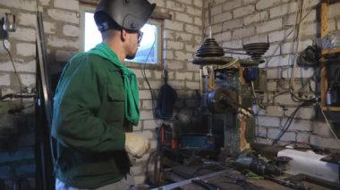 Koruyucu gözlüklü neşeli bir tamirci atölyede çalışırken aylaklık ediyor. Üniformalı mutlu tamirci garajda eğleniyor ve eğleniyor. Genç adam iş yerinde tuhaf dans ediyor. Dolly vurdu..