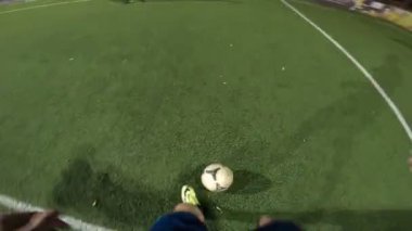 Futbolcunun akşam saatlerinde futbol sahasında antrenman yapmasına bakış açısı. Adam topa sürüp rakibine vurmaya çalışıyor. Adam topu arkadaşına atıyor. Boş zaman konsepti. POV.