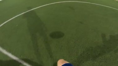 Futbolcunun akşam saatlerinde futbol sahasında antrenman yapmasına bakış açısı. Adam topa sürüp rakibine vurmaya çalışıyor. Adam topu arkadaşına atıyor. Boş zaman konsepti. POV.
