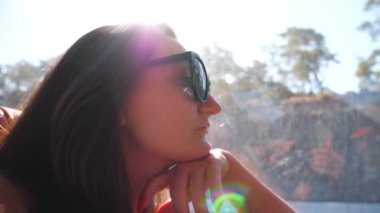 Güneşli bir günde otobüsle seyahat eden ve pencereye bakan güneş gözlüklü genç esmerin profili. Yolculuk sırasında çevreye hayran olan bir bayan yolcu. Arka planda güneş ışığı olan bir kadın arabayla seyahat ediyor..