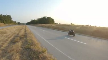 Otoyolda motorsiklet süren kasklı motosikletliyi takip edin. Adam sonbahar kır yolunda motosikletiyle yarışıyor. Yolculuk sırasında bisiklet süren adam. Özgürlük ve macera kavramı. Hava görüntüsü.