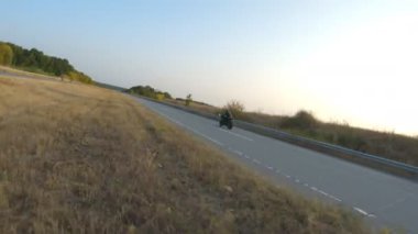 Güneşli bir günde taşra yolunda modern motosiklet süren bir adam. Motosikletli otoyolda motosikletiyle yarışıyor. Yolculuk sırasında bisiklet süren bir adam. Seyahatte özgürlük ve macera kavramı. Hava görüntüsü.