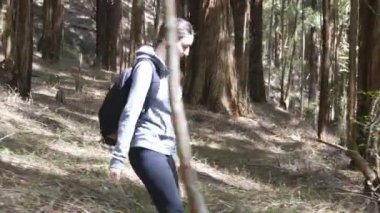 Kadın backpacker yaz tatili seyahat sırasında ahşap geçiyor. Ormanda yürüyen sırt çantası ile genç kadın turist. Doğada yürüyüş kız. Sağlıklı aktif yaşam tarzı kavramı. Yan görünüm.