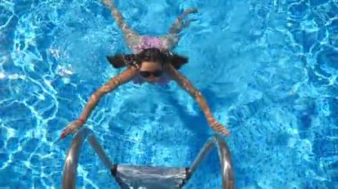 Attractive woman in pink bikini getting out of pool. Young sexy girl enjoying summer vacation refreshing in basin. Lady in sunglasses relaxing on resort. Travel or holiday concept. Slow mo Top view.