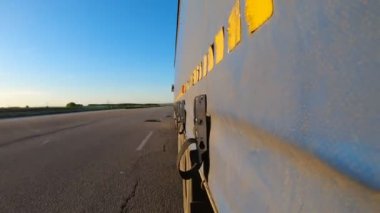 Asfalt yolda mal taşıyan bir kamyon. Kırsal kesimde hareket eden bir kamyon römorkundan diğerine bir bakış açısı. Hedefe giden ticari bir araba. Kargo taşımacılığı kavramı. Zaman aşımı.