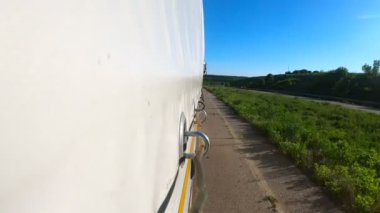 Güneşli bir günde asfalt yolda mal taşıyan bir kamyon. Kırsal bölgede hareket eden bir kamyon römorkundan diğerine. Hedefe giden ticari bir araba. Kargo taşıma konsepti. Yavaş çekim.