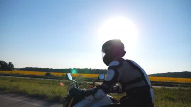 Otoyolda kasklı ve hızlı motorsiklet süren bir adam. Motosikletli doğa manzarasına karşı motosikletiyle yarışıyor. Koruyucu ekipmanlı adam yolculuğun tadını çıkarıyor. Macera ya da özgürlük kavramı. Yan görünüm.