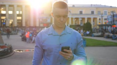 Kentsel caddede duran gömlekli başarılı bir işadamı ve arka planda şehir manzarası olan akıllı telefonlara göz atıyor. Kendine güvenen bir adam telefonunda uygulama kullanıyor. Dışarıda bir şeyler okuyan yakışıklı bir adam. Yavaş çekim