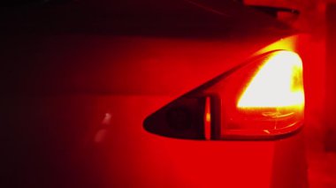 Kadın el, gece vakti şarj aletini elektrikli arabaya takıyor. Genç bir kadının kolu akşam şarj istasyonuna elektrik fişi takıyor. Modern teknoloji ve ekoloji dostu ulaşım kavramı.