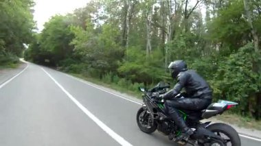 Orman yolundaki motosikletli motorcuları takip edin. Kasklı adam ormanın yakınındaki kırsal yolda modern spor motosiklet yarışı yapıyor. Yolculuk sırasında ya da yolculukta bisiklet süren adam. Özgürlük kavramı.