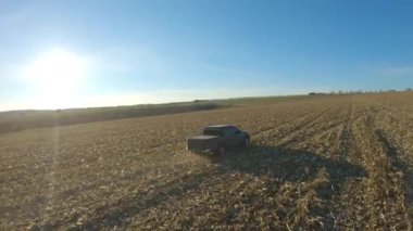 Hasattan sonra tarladan geçen kamyonetin hava görüntüsü. Güneşli bir günde çayır boyunca giden off-road aracı. Gündüz vakti tarlaların arasında uçan bir araba. Manzara kırsal görünümü.