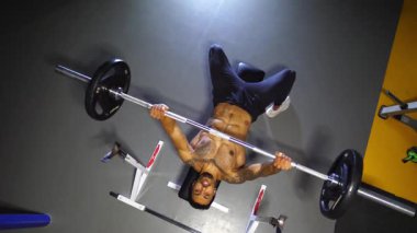 Güçlü siyah sporcu spor kulübünde halterle ağırlık çalışması yapıyor. Modern spor salonunda halter egzersizleri yapan kaslı Afro-Amerikan sporcu. Sağlıklı ve aktif yaşam tarzı konsepti. Üst