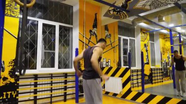 Spor salonunda egzersiz yapmadan önce ellerini esneten kaslı bir sporcu. Genç güçlü sporcu modern spor salonunda sıkı çalışmadan önce ısınıyor. Sağlıklı ve aktif yaşam tarzı kavramı. Yavaş çekim.