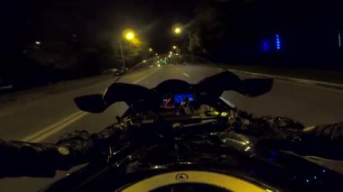 Aydınlanmış şehirde gece vakti bisiklet süren motosikletli bir erkek. Akşamları yüksek hızda motosiklet kullanan motosikletli birinin bakış açısı. Özgürlük kavramı. POV.