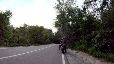 Kasklı adam ormanın yakınındaki kırsal yolda motorsikletle gezmeye başlıyor. Motosikletliler Woodland Country Road 'da motorsiklet sürmeye başlıyorlar. Yolculuk sırasında bisiklet süren adam. Macera kavramı. Havadan