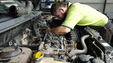 Erkek tamirci garajda arabanın bakımını yapıyor. Yetişkin oto tamircisi atölyede aracın kaputunun altında çalışıyor. İş yerinde otomobil teftişi yapan profesyonel bir tamirci. Aktarım tanısı.