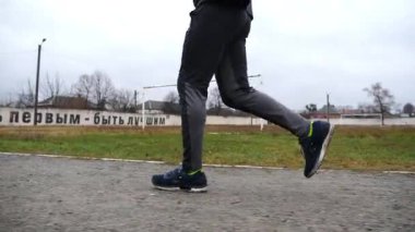 Atletizm sahasında koşan genç sporcuların bacakları. Erkek ayaklı spor koşucusu okul stadyumunda koşuyor. Açık havada güçlü ve dayanıklı bir sporcu antrenmanı. Etkin yaşam tarzı kavramı.