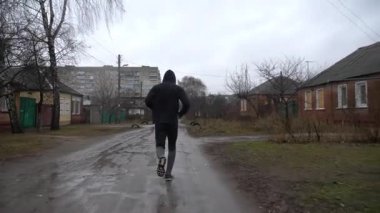 Yağmurda kır yolunda koşan güçlü bir atlet. Genç sporcu bulutlu bir günde kırsal alanda koşuyor. Atletik sporcu dışarıda egzersiz yapıyor. Sağlıklı aktif yaşam tarzı kavramı. Kapat..