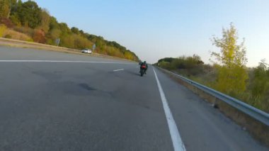 Güneşli bir günde taşra yolunda modern motosiklet süren bir adam. Motosikletli otoyolda motosikletiyle yarışıyor. Yolculuk sırasında bisiklet süren bir adam. Seyahatte özgürlük ve macera kavramı. Hava görüntüsü.