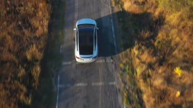 Yaz akşamları kır yolunda uçan elektrikli arabanın görüntüsü. Yeni bir SUV aracı otoban boyunca hızla ilerliyor. Çevre temiz otomobil otoyol boyunca elektrik yüküne biniyor. Üst Görünüm Yavaş Çekim.
