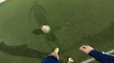 Futbolcunun akşam saatlerinde futbol sahasında antrenman yapmasına bakış açısı. Adam topa sürüp rakibine vurmaya çalışıyor. Adam topu arkadaşına atıyor. Boş zaman konsepti. POV.