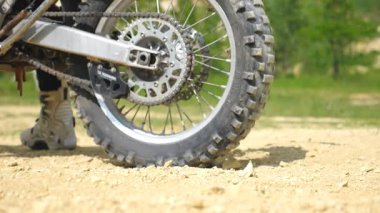Güçlü off-road motorsiklet tekerlerini kapat ve hareket başlat. Motokros motoru hareket etmeye başlıyor. Kuru toprak ya da etrafta uçuşan toz. Motor sporu ya da aktif yaşam tarzı kavramı. Yavaş çekim kenar görünümü.
