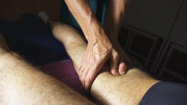 Salonda genç sporcunun şifa rubdown ayak yapıyor masagist üst görünümü erkek elleri. Salonda masaj masasına yatan sporcunun profesyonel masör masaj bacak Kolları. Yavaş çekim.
