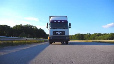 Otoyolda giden bir kamyonun ön görüntüsü. Kamyon arka planda güzel bir manzarayla kırsal alanda ilerliyor. Yavaş çekim. Yakın çekim..