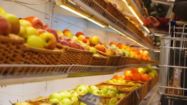 Markette taze meyveli rafların manzarası. İnsanlar arka planda ürünleri seçiyor. Müşteriler sağlıklı yiyecekler alıyor. Süpermarkette çeşitli ürünler. Alışveriş konsepti. Yavaş çekim.