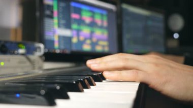 Ses kayıt stüdyosundaki synthesizer 'da çalan erkek müzisyenin elleri. Mens arms solo müzik ya da yeni melodi çalıyor. Piyanistin parmaklarını piyano tuşlarına yakın tut. Yavaş çekim.