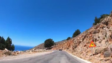 Deniz kıyısına yakın otobanda otomobil kullanma bakış açısı. Araba deniz kenarındaki yılan güzergahında. Arka planda dağlarda kayalar olan güzel bir manzara. Trip konsepti. Ön görünüm zaman aşımı.